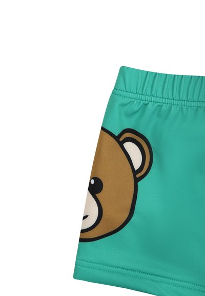 Pantaloni da bagno turchesi con una cintura elastica che presenta un grande design di testa d'orso in marrone e nero. Tessuto morbido e leggero.