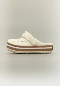 Μπεζ και καφέ παπούτσι Crocs με οπές αερισμού και ρυθμιζόμενο λουράκι στη φτέρνα σε ουδέτερο φόντο, πλευρική όψη.