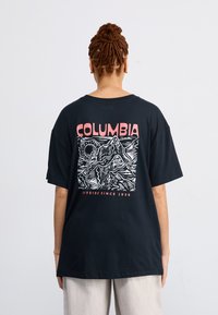 Black oversized t-shirt with a white mountain graphic and "COLUMBIA" in pink on the back, short sleeves, and a relaxed fit.