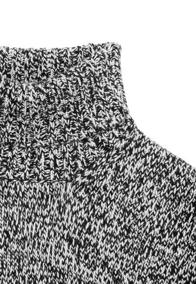 Juodos ir baltos spalvų margas megztinis su aukšta apykakle, rodantis raštuotą audinį ir tapišinę apykaklę.