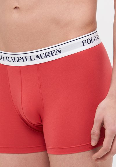 Boxers de algodão vermelhos com uma faixa branca apresentando o texto "POLO RALPH LAUREN" em azul-marinho. Textura suave, design justíssimo.