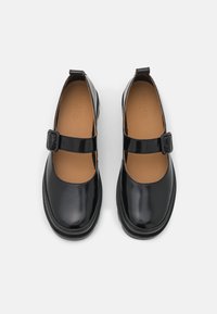 Schwarze Lackleder-Mary-Jane-Schuhe mit runder Zehe, Knöchelriemen und braunem Innensohle. Flache Sohle und minimalistisches Design.