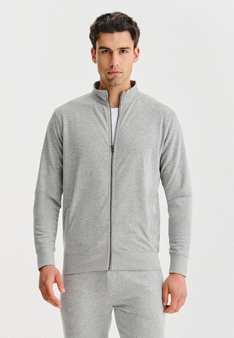 Szara kurtka na zamek wykonana z miękkiego materiału, z wysokim kołnierzem, długimi rękawami i przednimi kieszeniami. W komplecie z dopasowanymi spodniami.