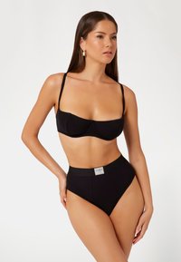 Čierny bikiny set s textúrovaným povrchom. Vrchná časť má vystužený dizajn s nastaviteľnými ramienkami, zatiaľ čo nohavičky s vysokým pásom majú logovú nálepku.