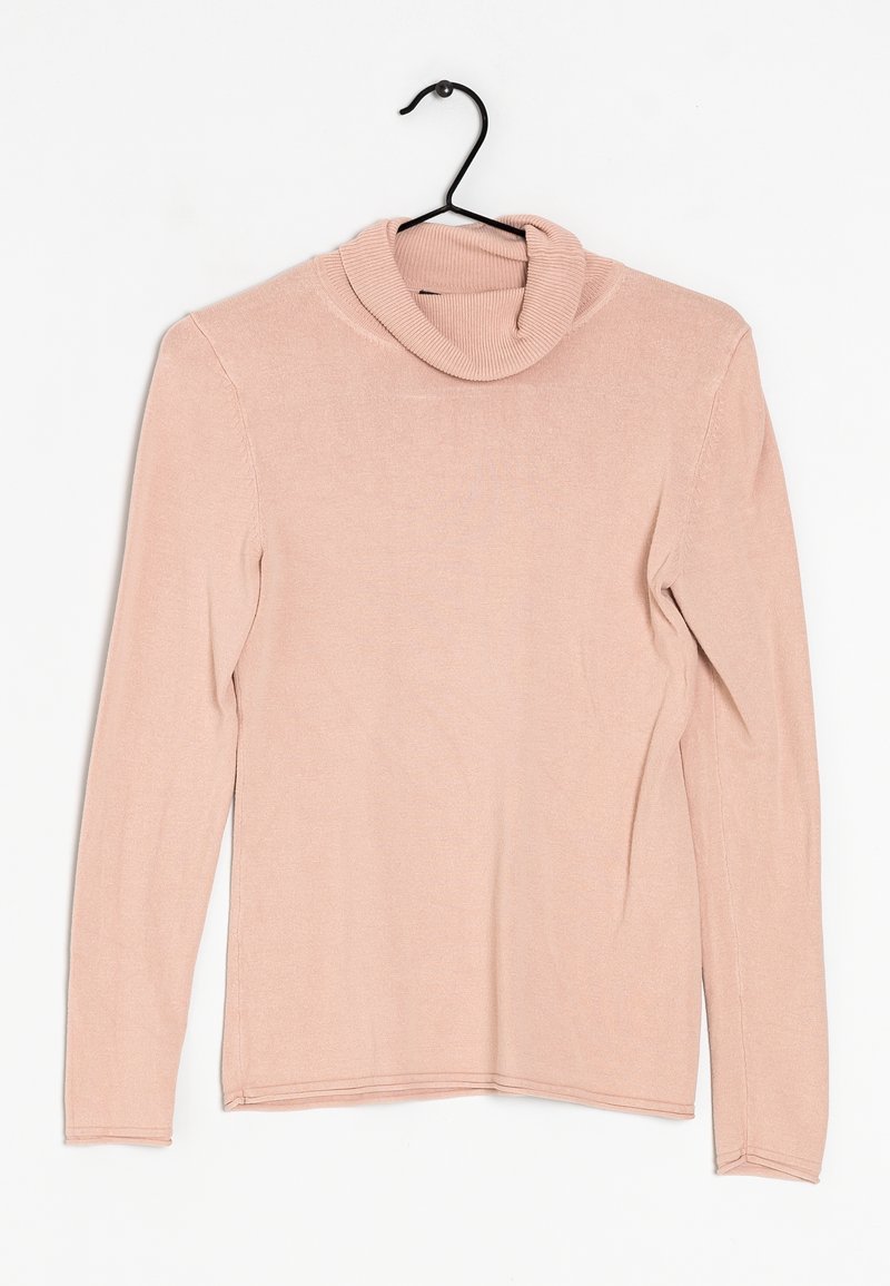 Pull rose clair à manches longues et col roulé suspendu à un cintre noir sur fond blanc.