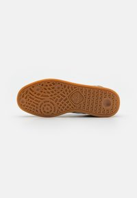 Brown rubber outsole with textured surface and circular patterns. Features a heart logo and brand name "hummel" embossed.