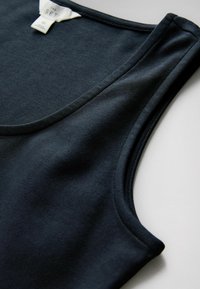 Donkerblauwe mouwloze top met ronde hals, gemaakt van zachte stof, plat neergelegd met zichtbare neklabel en details van de armsgatnaden.