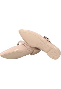 Tacones de charol nude con punta afilada, fina correa en el tobillo y tacón cuadrado; presenta un sutil logo en la suela.