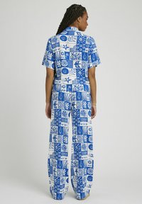 Ensemble bleu et blanc en deux pièces avec des motifs en blocs inspirés de la nature, chemise à manches courtes et pantalon large. Tissu texturé.