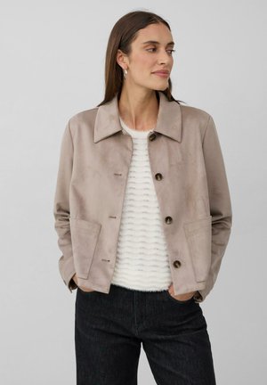 Light beige suede jacket with a collar, front buttons, and two pockets. Worn over a textured white sweater, paired with black jeans.