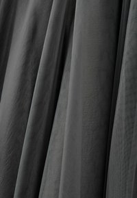 Hall hall, mis on voolavad draped, näitab pehmet tekstuuri ja õrnalt läiget. Mitmed kihid loovad kihilise, õhulise välimuse.