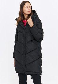 Czarna kurtka puchowa z kapturem, z charakterystycznym wzorem w zygzak, klapą i sznurkami do regulacji. Teksturowany materiał z zamkiem błyskawicznym i zatrzaskami.