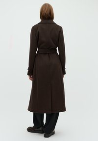 Brown wool coat with a belt, long sleeves, and a collar. The design features a smooth texture and a mid-calf length. Back view shown.