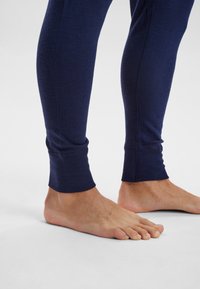 Marineblaue lange Leggings aus einem weichen, dehnbaren Material, mit einer subtilen Textur und eng anliegenden Knöchelbündchen, präsentiert mit baren Füßen.