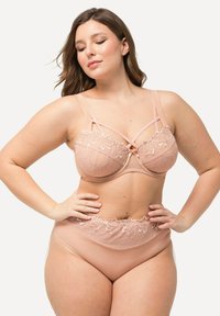Blush beha met kantafwerking en beugel, versierd met delicate bloemenborduring, gecombineerd met bijpassende hoogoplopende slipjes met vergelijkbare kantaccenten.