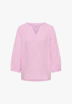 Jasnoróżowa damska bluzka z rękawami do łokcia i dekoltem w serek, wykonana z teksturowanego materiału, z metką "CECIL" wewnątrz kołnierzyka.