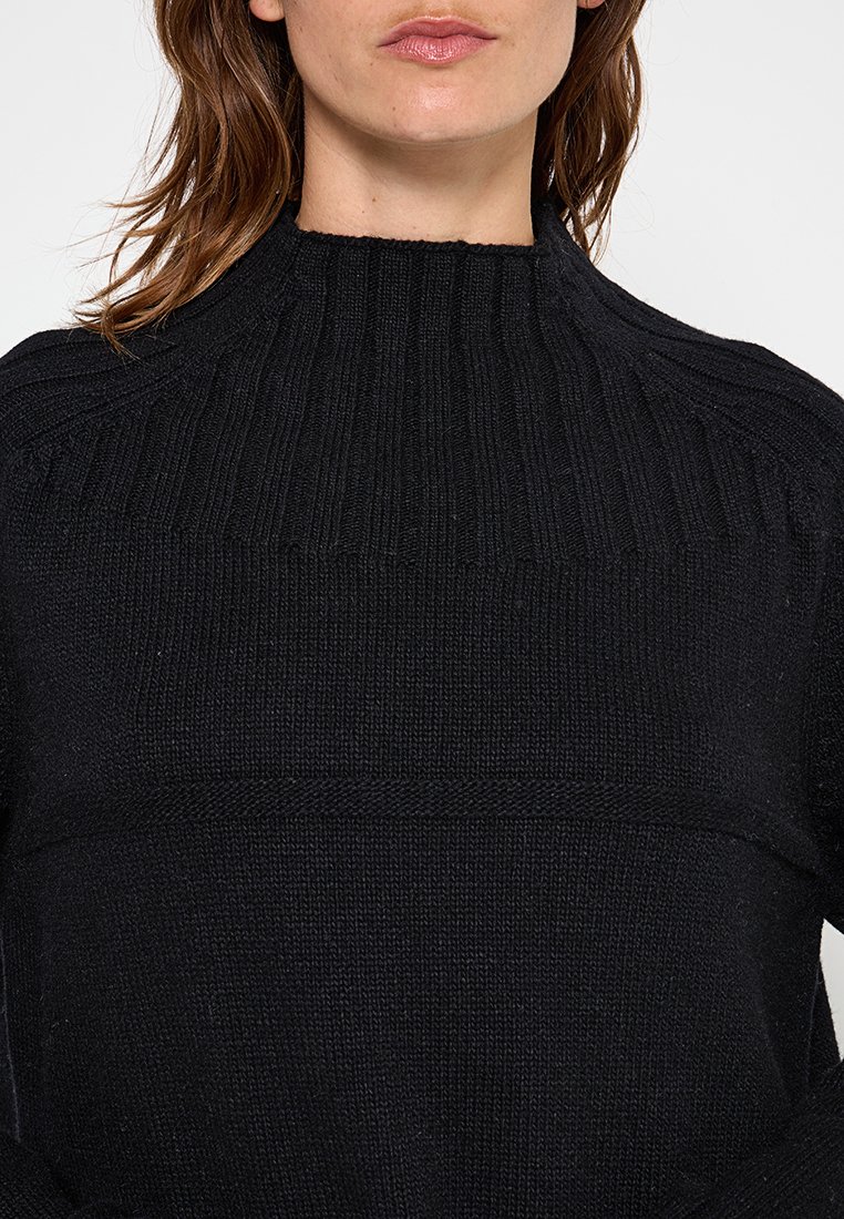 Schwarzer Strickpullover mit hohem geripptem Kragen, strukturiertem Körper und einem kontrastierenden horizontalen Streifen. Verfügt über lange Ärmel und eine lässige Passform.