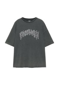 T-shirt oversize gris foncé à manches courtes avec texte blanc stylisé en police dentelée sur la poitrine.