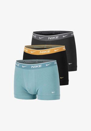 Tres pares de bóxers Nike: uno negro con cintura gris, otro negro con cintura naranja y otro azul claro con cintura azul, cada uno con el logo de Nike Swoosh.