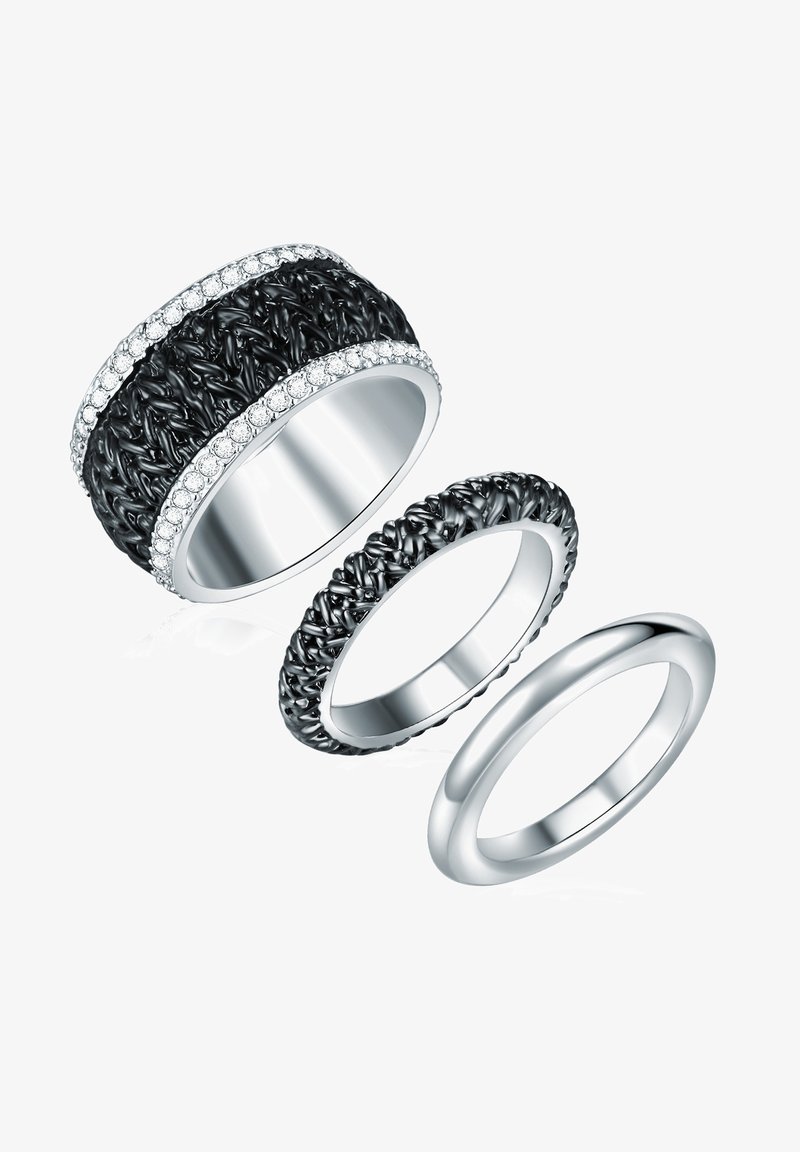 Tre ringar staplade tillsammans: en bred texturerad svart ring med klara stenar, en flätad svart ring och en slät silverring.