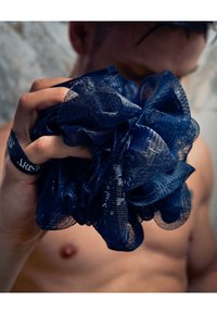 Marineblå netbrusebørste holdt i en hånd, med en rynket tekstur bestående af lagdelte løkker og en blød finish.