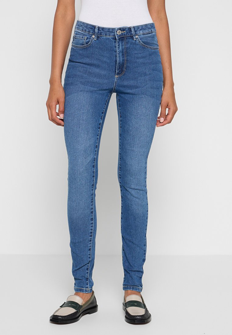 Skinny denim jeans in een middelmatige blauwe was, met een vijf-pocket ontwerp, riemlussen en subtiele vervaging. Gecombineerd met zwartgroene instappers.