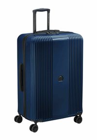 Valigia rigida blu navy con scanalature verticali, manico estraibile e quattro ruote nere per la mobilità. Presenta una chiusura con zip e una maniglia laterale.