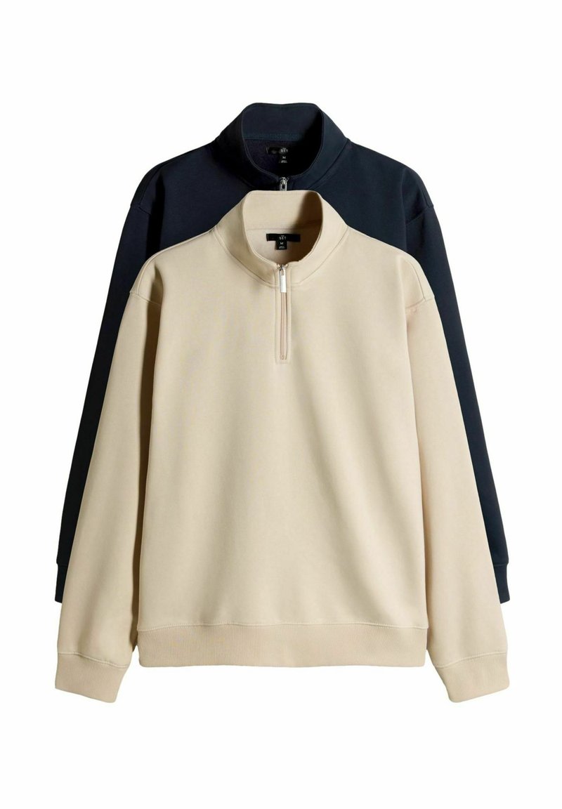 Dwie bluzy typu quarter-zip, jedna beżowa z przodu, a druga czarna z tyłu, obie z długimi rękawami i stojącymi kołnierzami na białym tle.