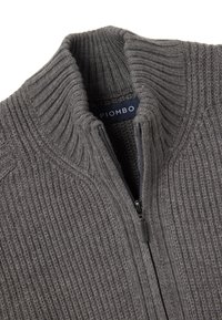 Grijze gebreide ritstrui met een ribbeltextuur en hoge kraag. Label zegt "PIOMBO." Bevat een rits en heeft een gestroomlijnde vorm.