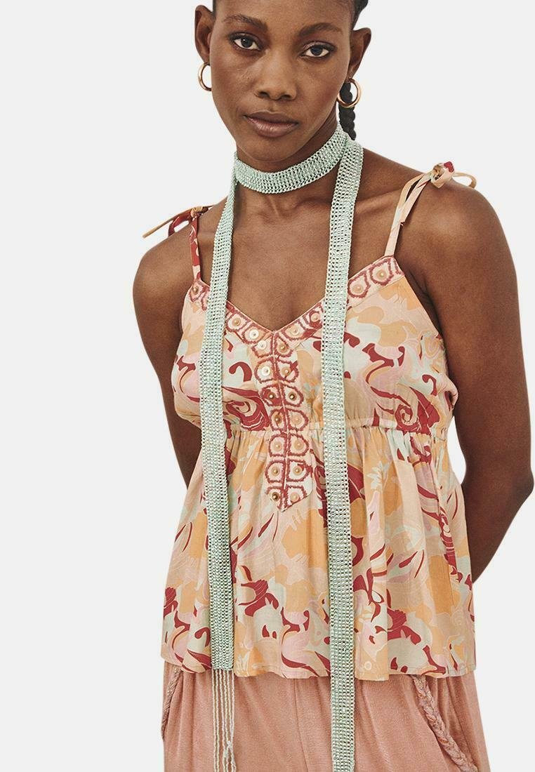 Top sin mangas de estampado floral en tonos durazno con un cuerpo fruncido, escote detallado y tirantes finos. Presenta un acento texturizado.