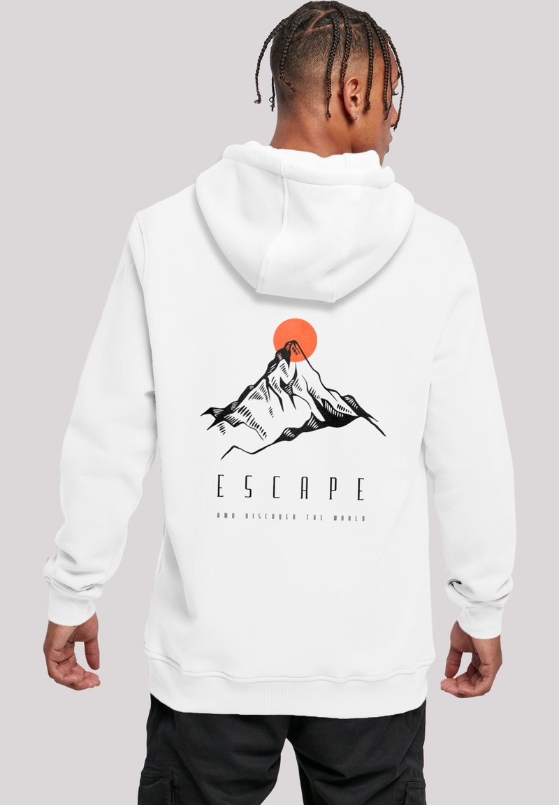 Person with braided hair wearing a white hoodie with a mountain and orange sun graphic and the word "ESCAPE" on the back.