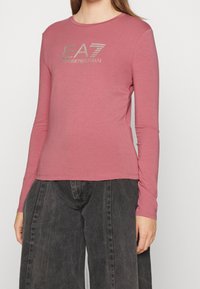 Långärmad rosa skjorta i mjukt tyg med en silverfärgad EA7-logotyp på bröstet, rund halsringning och figurnära silhuett.