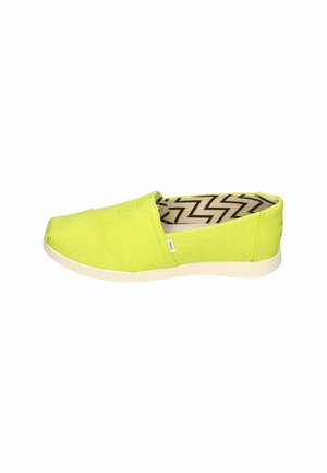 Green canvas slip-on shoes with a textured surface, featuring a light-colored rubber sole and a zigzag pattern lining.
