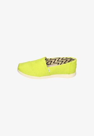 Green canvas slip-on shoes with a textured surface, featuring a light-colored rubber sole and a zigzag pattern lining.