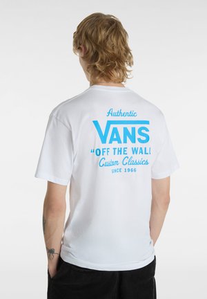 White cotton t-shirt featuring blue graphic text on the back that reads "Authentic VANS 'OFF THE WALL' Custom Classics since 1966."
