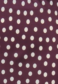 Tissu bordeaux avec des pois blancs uniformément espacés. La texture est lisse, ce qui met en valeur le motif.