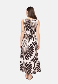 Maxikleid mit einem schwarz-weißen Blumenmuster, ärmellosem Design, Taillenbindung und Knopfdetail im Rücken. Glattes Material mit fließender Form.