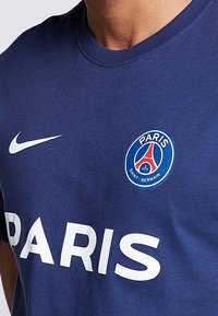 Námořnická modrá Nike tričko má na sobě v tučných bílých písmenech nápis "PARIS", s kruhovým logem PSG na levé části hrudi. Vyrobeno z měkké látky.