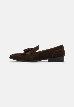 Dunkelbrauner Wildleder-Herrenloafer mit Quasten, niedrigem schwarzem Absatz und abgerundeter Spitze, von der linken Seite vor einfachem Hintergrund gezeigt.