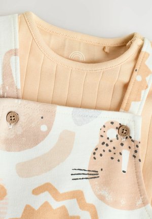 Beige outfit i bomull med en ribbad topp och hängslen med lekfulla djurmönster, träknappar och mjuka, släta texturer.