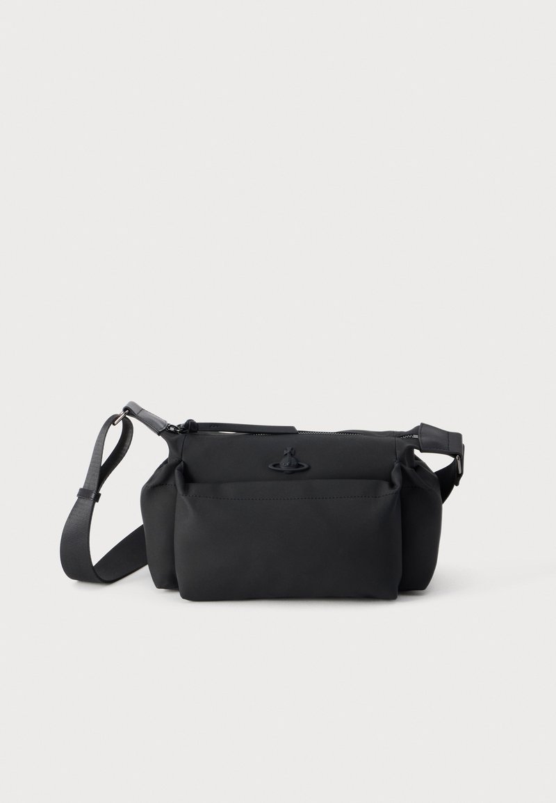 Μαύρο τσαντάκι crossbody με μπροστινή τσέπη, ρυθμιζόμενο λουράκι και κλείσιμο με φερμουάρ σε απλό ανοιχτόφωτο φόντο.