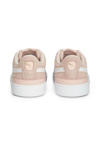 Puma lenkkarit, joissa on vaaleanpunainen anteeksi, valkoiset sivustripit ja valkoiset kumipohjat. Kullanvärinen logo korostus kantapäässä ja pehmeä kankainen vuori.