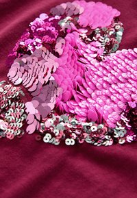 Tessuto borgogna con un design testurizzato di paillettes sovrapposte in diverse sfumature di rosa, rosso e argento, che creano un effetto scintillante.