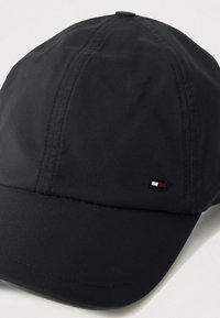 Black cap made from waterproof material; features a curved brim and a small logo with red, white, and blue colors on the front side.