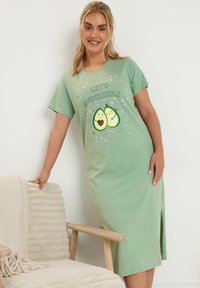 Grön bomullsnattlinne med korta ärmar, prytt med texten "Låt oss avokado-kela" och avokadografik. Sidslits och avslappnad passform.