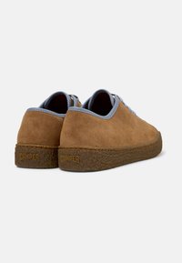 Ruskeat mokkanahkakengät, joissa on sileä pinta, vaaleansiniset korostukset kauluksessa ja kuvioitu ruskea pohja, jossa on "Camper"-logo.