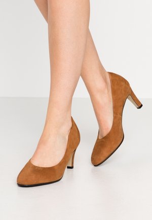 Chaussures à talons hauts en suédine marron avec un bout pointu et un talon fin, présentant une texture lisse et une couleur unie sans motifs.