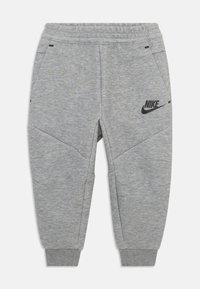 Sive Nike trenirke s elastičnim pojasom, sužene nogavice, bočne džepove i crni logo akcent na lijevom bedrima. Mekana tekstura tkanine.