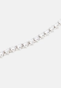 Sølvfarvet armbånd med cirkulære klare sten sat i kroneindstillinger, som skaber et kontinuerligt mønster langs hele længden af stykket.