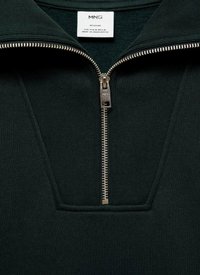Temnozelen zip-up pulover z visokim ovratnikom, ki ima srebrno kovinsko zadrgo in rebrasto teksturo. Na voljo je oznaka z informacijami o blagovni znamki.